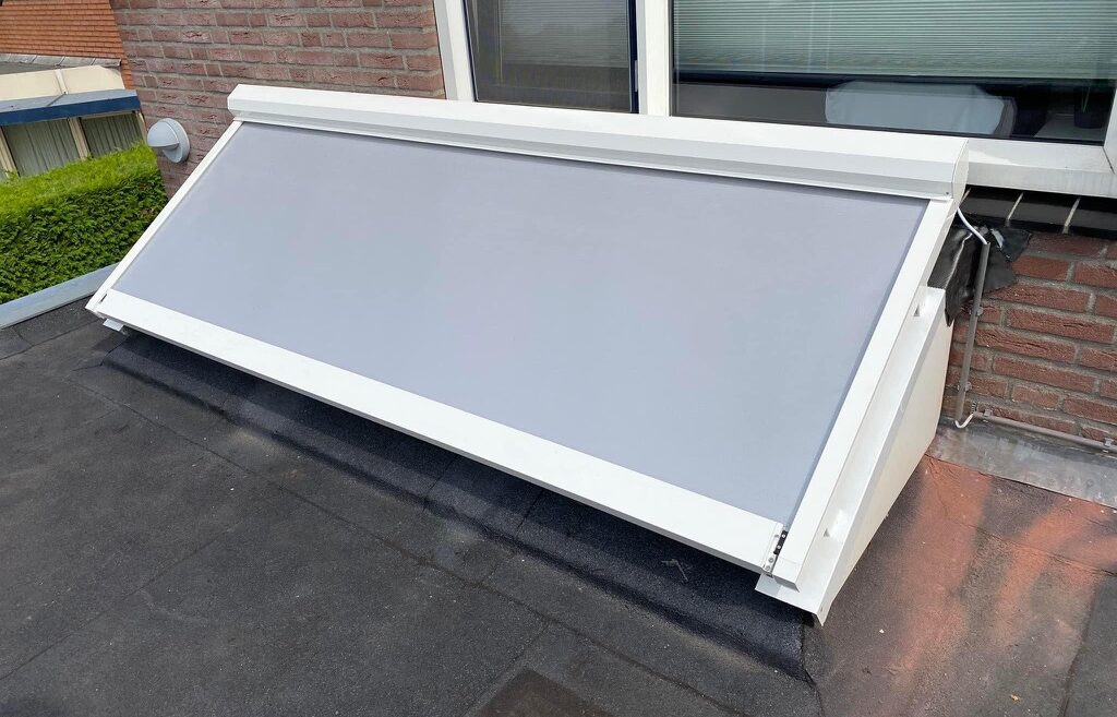 Bovendakse lichtstraatzonwering uitgevoerd in wit frame met licht grijs doek - in gebruik / cassette open