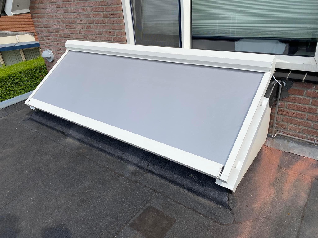 Bovendakse lichtstraatzonwering uitgevoerd in wit frame met licht grijs doek - in gebruik / cassette open
