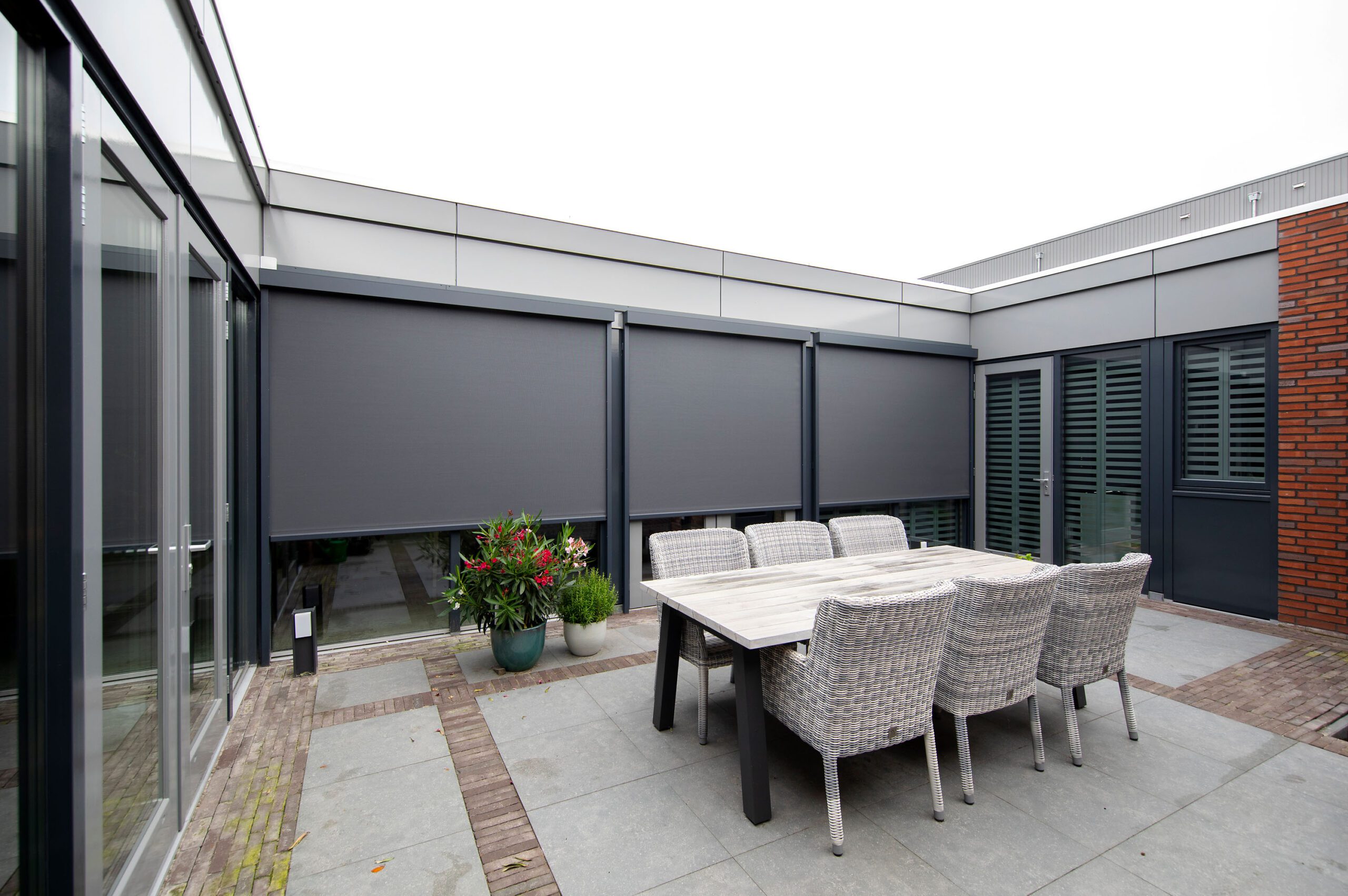 Buitenaanzicht zonnescreens en Fractions aluminium shutters aan moderne nieuwbouw bungalow in diverse gebruiksposities