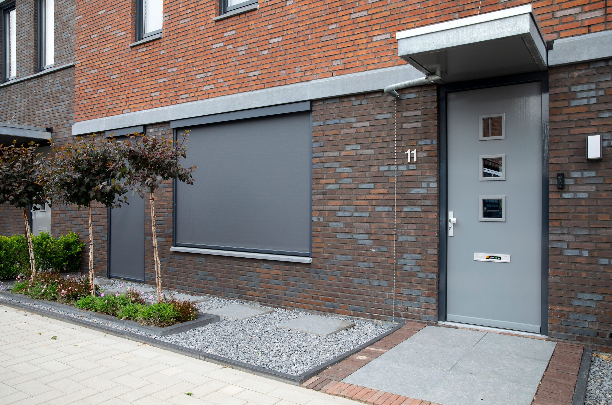 Buiten aanzicht antraciete zonnescreens over Fractions aluminium shutters aan nieuwbouw tussenwoning in gebruik