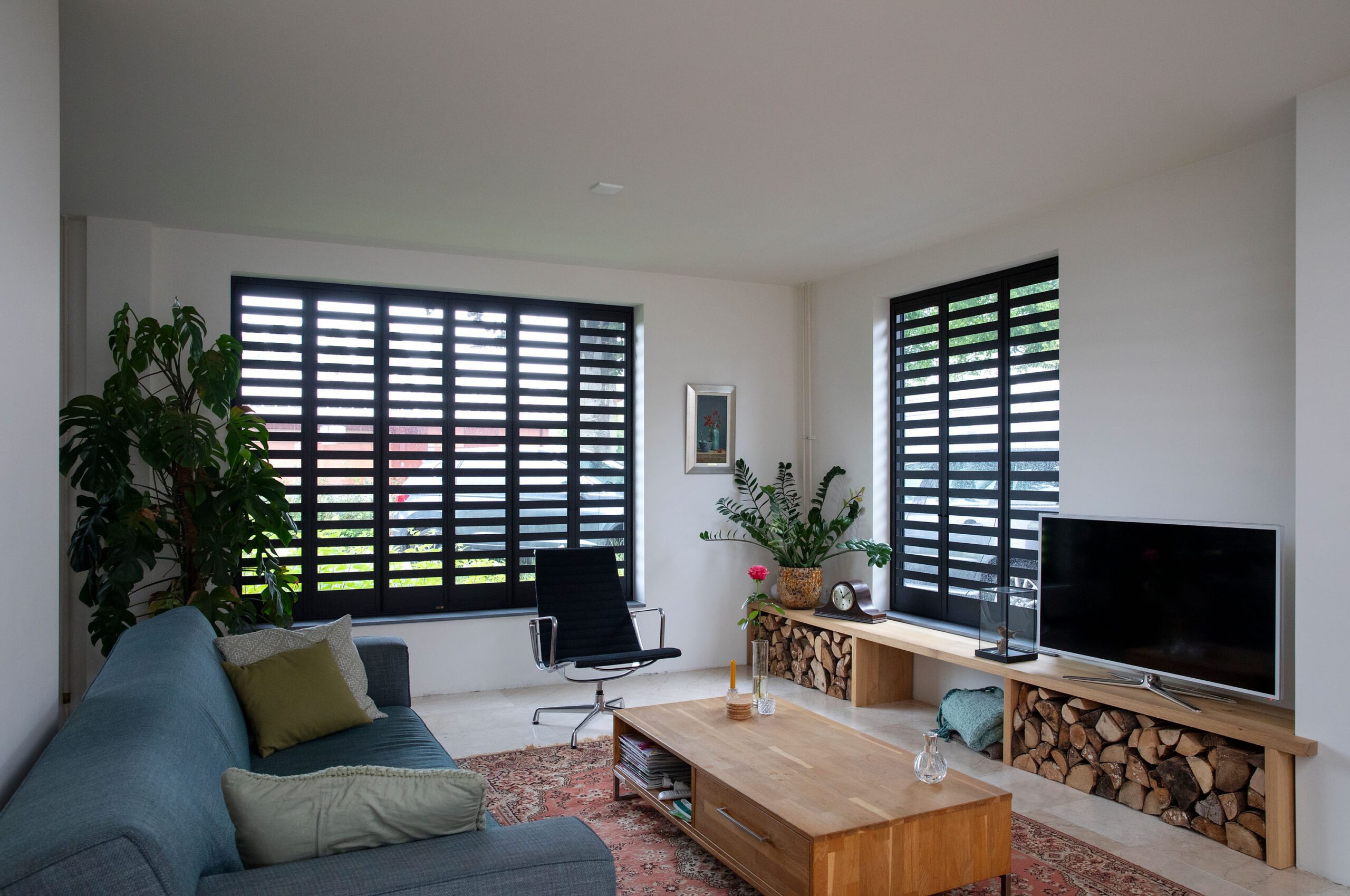 Combinatie zwarte Fractions aluminium shutters in Louvre patroon in gezellige moderne woonkamer